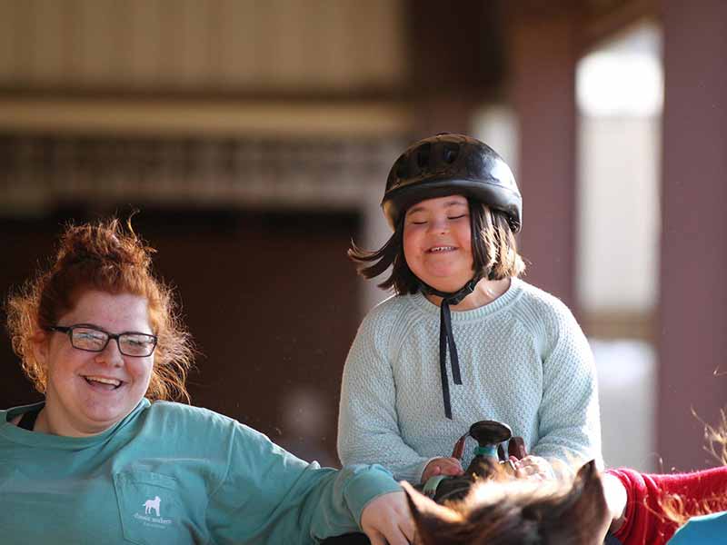 girl with black helmet on horseback with woman with red hair next to her
