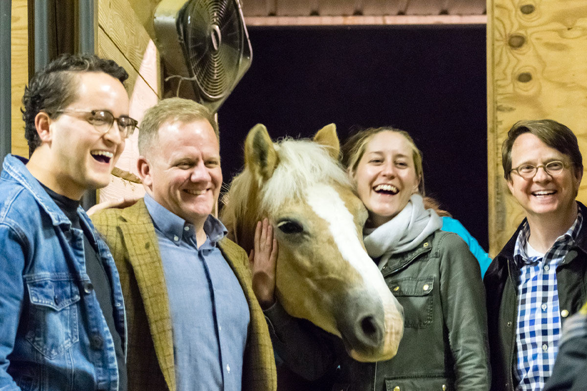 group of people smiling with horse
